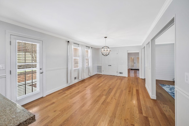 unfurnished dining area featuring a notable chandelier, light wood-style floors, visible vents, and crown molding