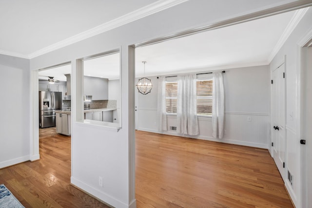 interior space featuring light wood-style floors, ornamental molding, stainless steel refrigerator with ice dispenser, and ceiling fan with notable chandelier