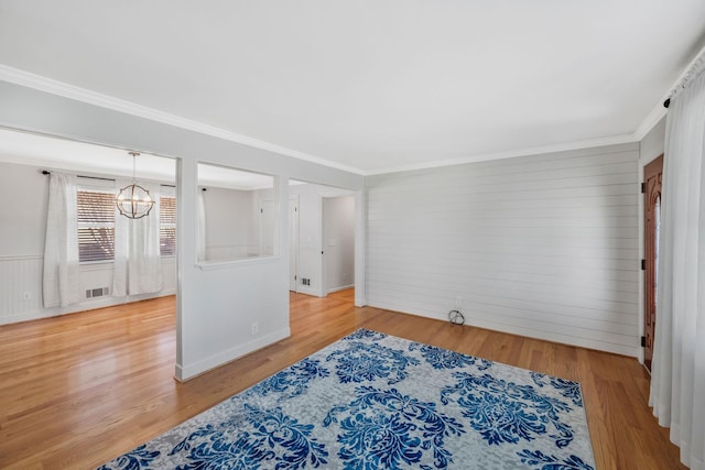 unfurnished room featuring an inviting chandelier, visible vents, wood finished floors, and ornamental molding