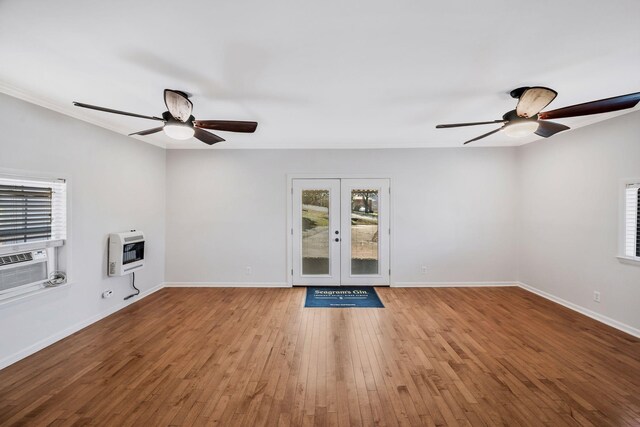 unfurnished living room featuring french doors, baseboards, light wood-style flooring, and heating unit