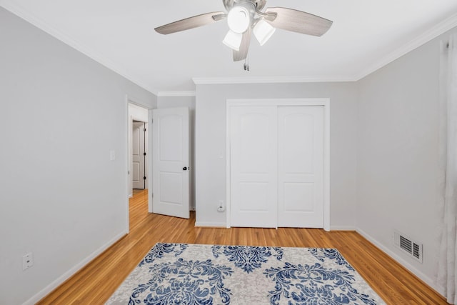 bedroom featuring baseboards, crown molding, visible vents, and wood finished floors