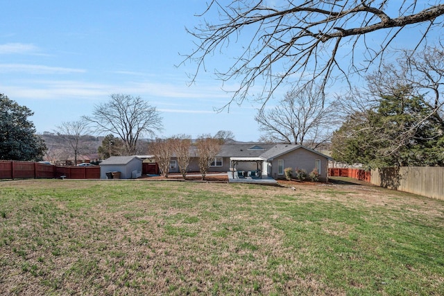 back of house featuring a fenced backyard, an outbuilding, and a yard