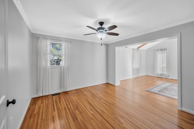 spare room with crown molding, baseboards, and light wood-style floors