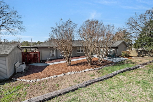 rear view of property featuring a gate, fence, and a yard