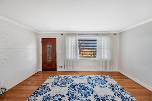 foyer featuring baseboards, ornamental molding, and wood finished floors