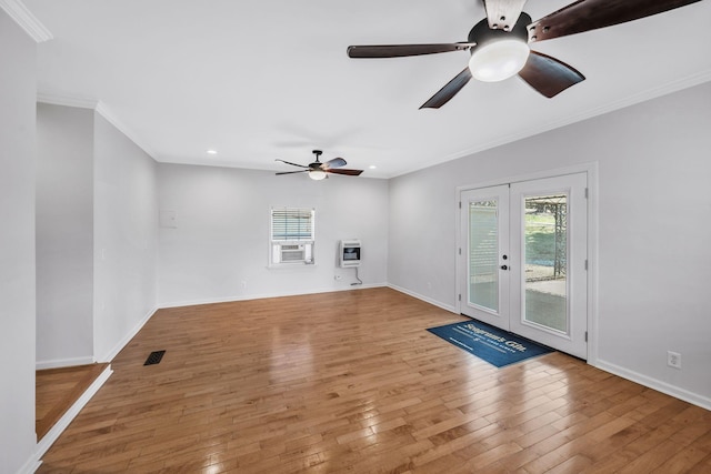 unfurnished living room with baseboards, french doors, light wood-type flooring, heating unit, and crown molding