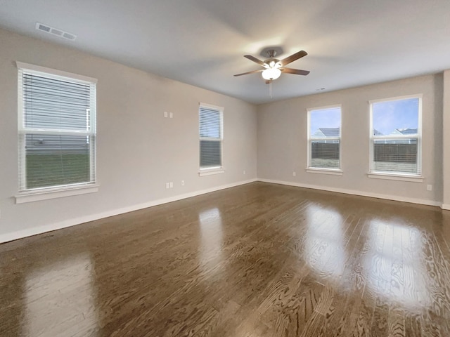 spare room with a ceiling fan, baseboards, visible vents, and dark wood-style flooring