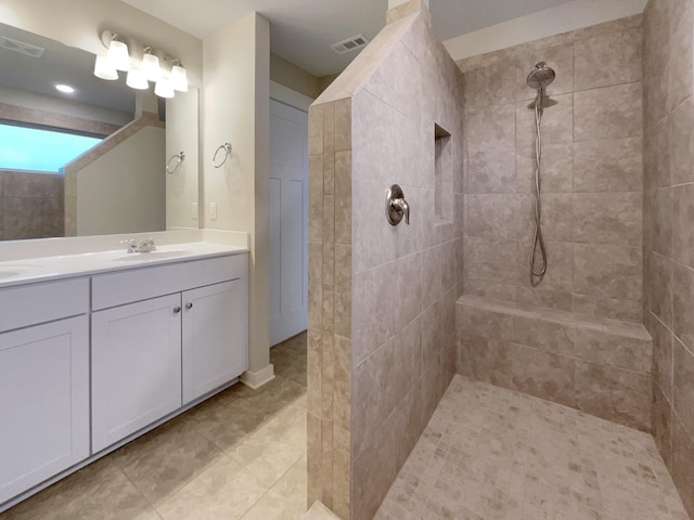 bathroom featuring visible vents, a sink, a tile shower, and double vanity