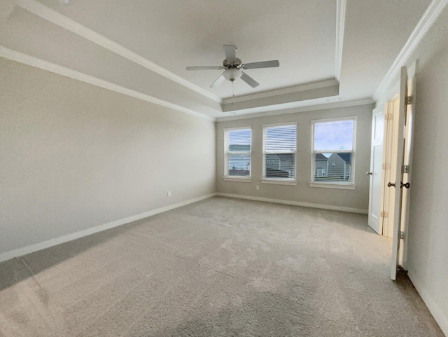 spare room featuring ornamental molding, a raised ceiling, light colored carpet, and baseboards