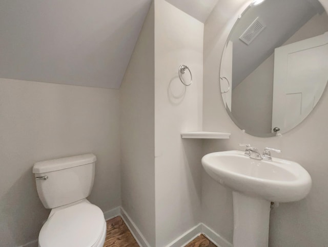 bathroom with baseboards, visible vents, toilet, wood finished floors, and vaulted ceiling