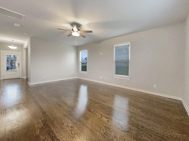 empty room featuring dark wood-style floors, visible vents, baseboards, and a ceiling fan