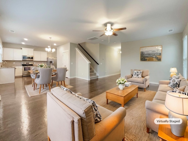 living room featuring dark wood-style flooring, stairway, visible vents, and baseboards