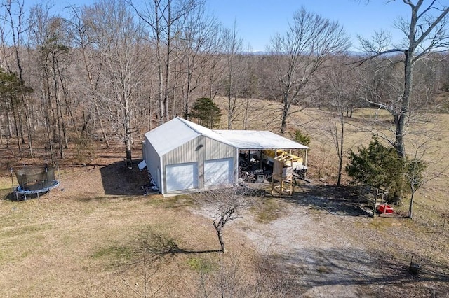 view of outbuilding featuring driveway, a trampoline, and an outdoor structure