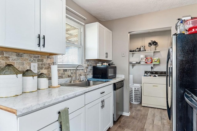 kitchen featuring stainless steel appliances, light wood-style flooring, decorative backsplash, white cabinetry, and a sink