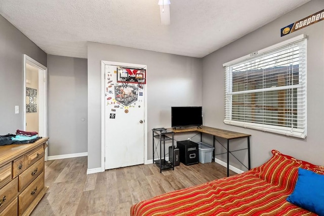 bedroom with light wood-style floors, a ceiling fan, baseboards, and a textured ceiling