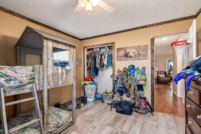 bedroom featuring a textured ceiling, ornamental molding, a closet, and light wood-style flooring