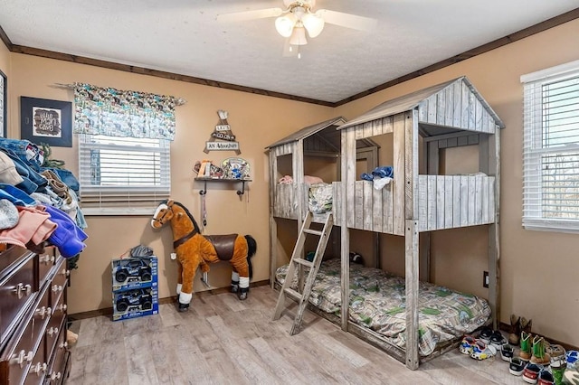 bedroom with ornamental molding, light wood finished floors, multiple windows, and baseboards