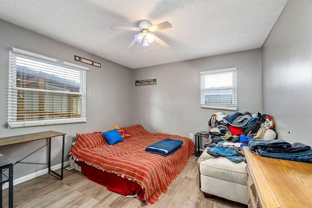 bedroom with ceiling fan, a textured ceiling, light wood-style flooring, and baseboards