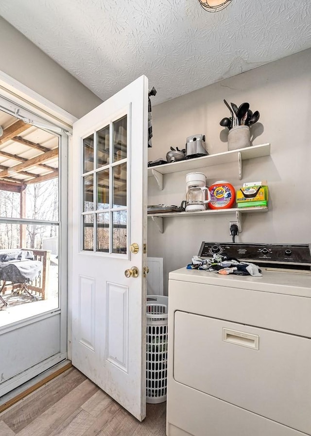 clothes washing area with a textured ceiling, laundry area, light wood finished floors, and washer / dryer