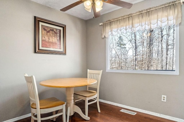 dining room with dark wood-style flooring, visible vents, ceiling fan, and baseboards