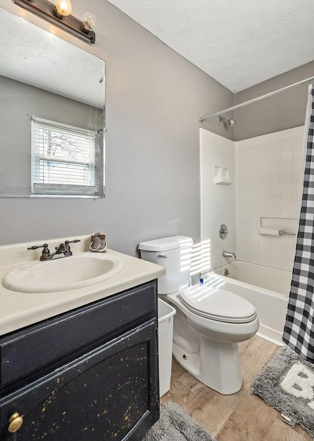 bathroom featuring toilet, wood finished floors, shower / bathtub combination with curtain, a textured ceiling, and vanity