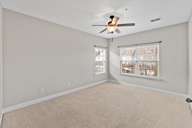 spare room featuring baseboards, visible vents, and light colored carpet