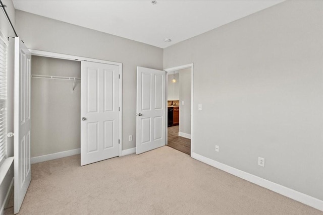 unfurnished bedroom featuring a closet, light carpet, and baseboards