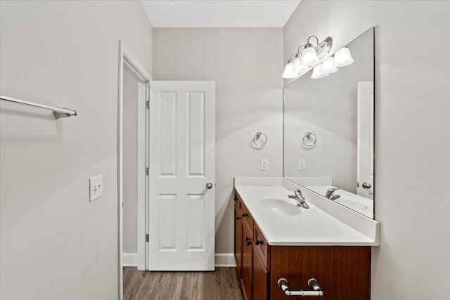 bathroom featuring baseboards, wood finished floors, and vanity