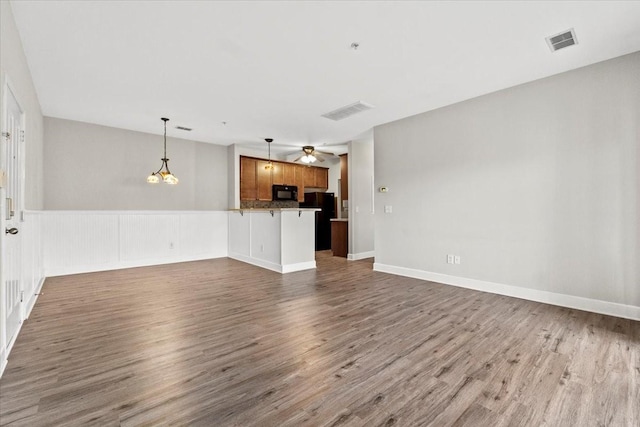 unfurnished living room with dark wood-style floors, baseboards, visible vents, and a ceiling fan