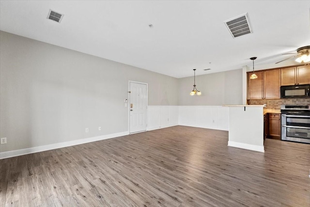 interior space featuring black microwave, range with two ovens, visible vents, open floor plan, and light countertops