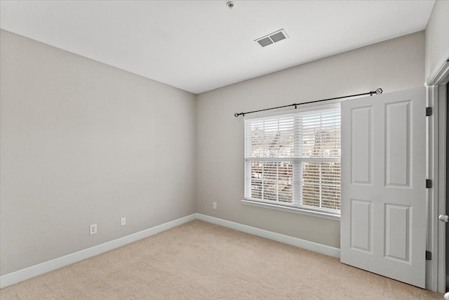 unfurnished room featuring light carpet, visible vents, and baseboards