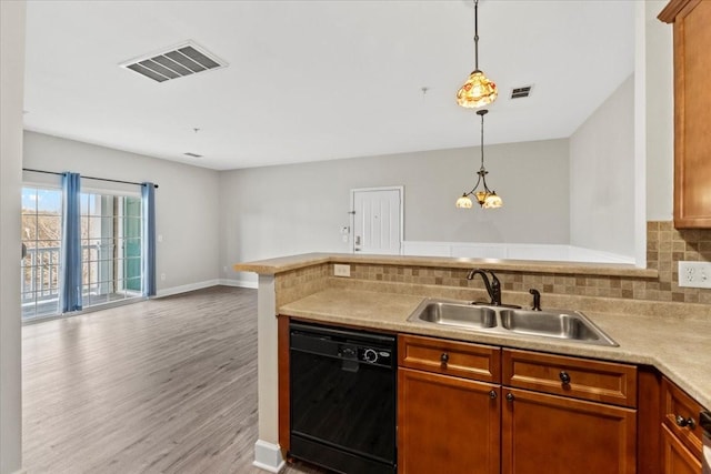 kitchen featuring black dishwasher, visible vents, hanging light fixtures, light countertops, and a sink