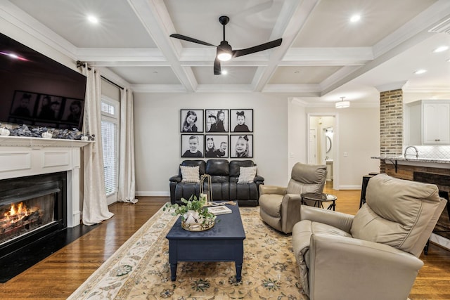 living room featuring wood finished floors, beamed ceiling, coffered ceiling, and a fireplace with flush hearth