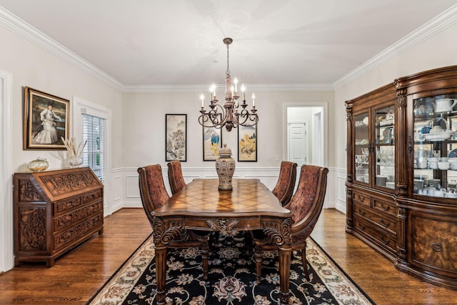 dining space featuring a chandelier, ornamental molding, wood finished floors, and wainscoting