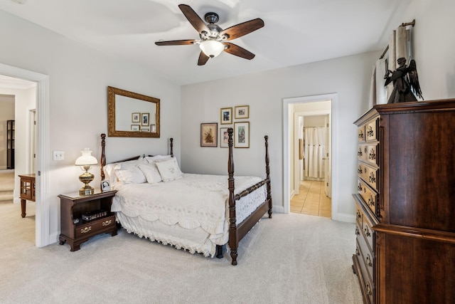 bedroom with ensuite bath, baseboards, a ceiling fan, and light colored carpet