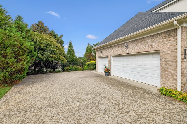 view of property exterior featuring driveway, brick siding, and roof with shingles