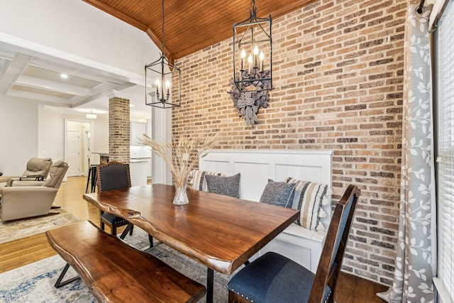 dining room featuring light wood-style flooring, brick wall, wooden ceiling, coffered ceiling, and ornate columns