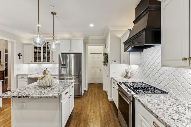 kitchen featuring a center island, stainless steel appliances, custom range hood, glass insert cabinets, and white cabinetry