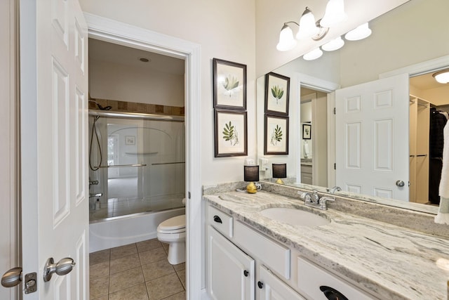 full bathroom with bath / shower combo with glass door, vanity, toilet, and tile patterned floors