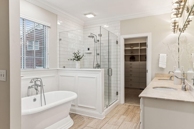 full bathroom featuring a freestanding bath, double vanity, ornamental molding, and a shower stall