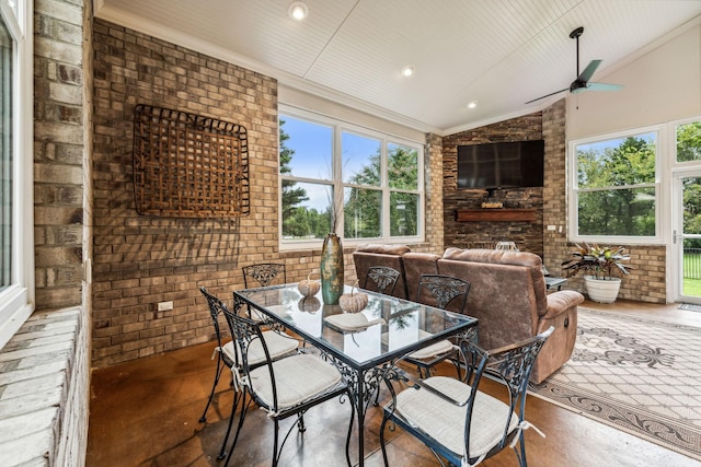 dining area with vaulted ceiling, brick wall, concrete floors, and plenty of natural light