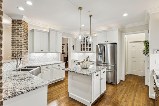 kitchen featuring decorative light fixtures, white cabinetry, a kitchen island, a sink, and stainless steel fridge with ice dispenser