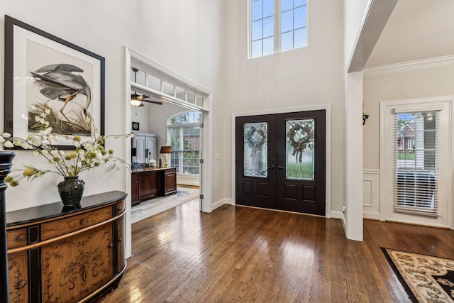 foyer entrance featuring baseboards, dark wood finished floors, ornamental molding, a high ceiling, and french doors