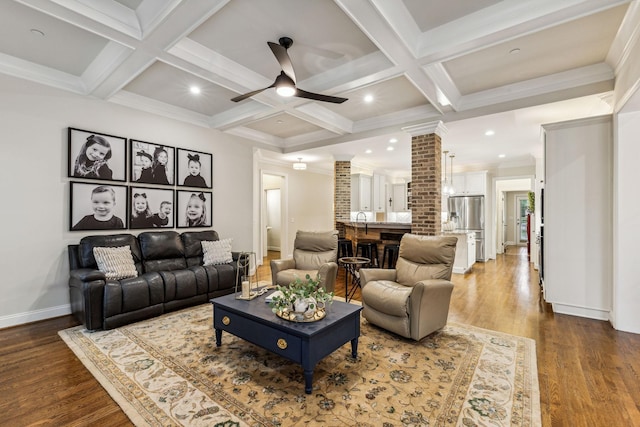 living area featuring beamed ceiling, wood finished floors, a ceiling fan, and ornate columns