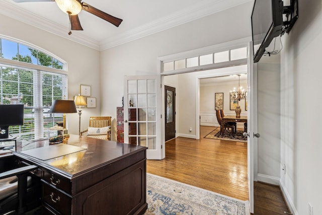 office space featuring ornamental molding, ceiling fan with notable chandelier, baseboards, and wood finished floors