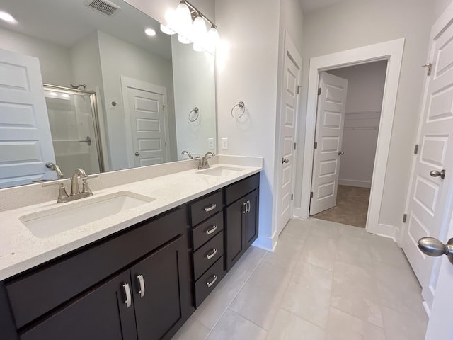 full bathroom with double vanity, a spacious closet, a sink, and visible vents