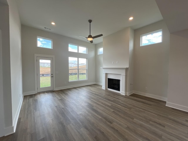 unfurnished living room with plenty of natural light, baseboards, visible vents, dark wood-style floors, and a fireplace