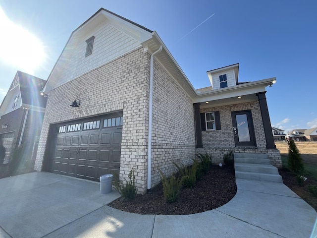 view of front of home featuring a garage, concrete driveway, and brick siding