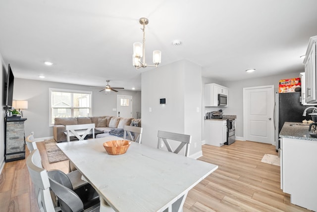 dining space with baseboards, ceiling fan with notable chandelier, light wood-type flooring, and recessed lighting