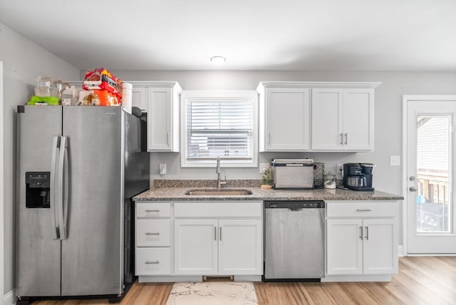 kitchen with appliances with stainless steel finishes, a healthy amount of sunlight, white cabinetry, and a sink